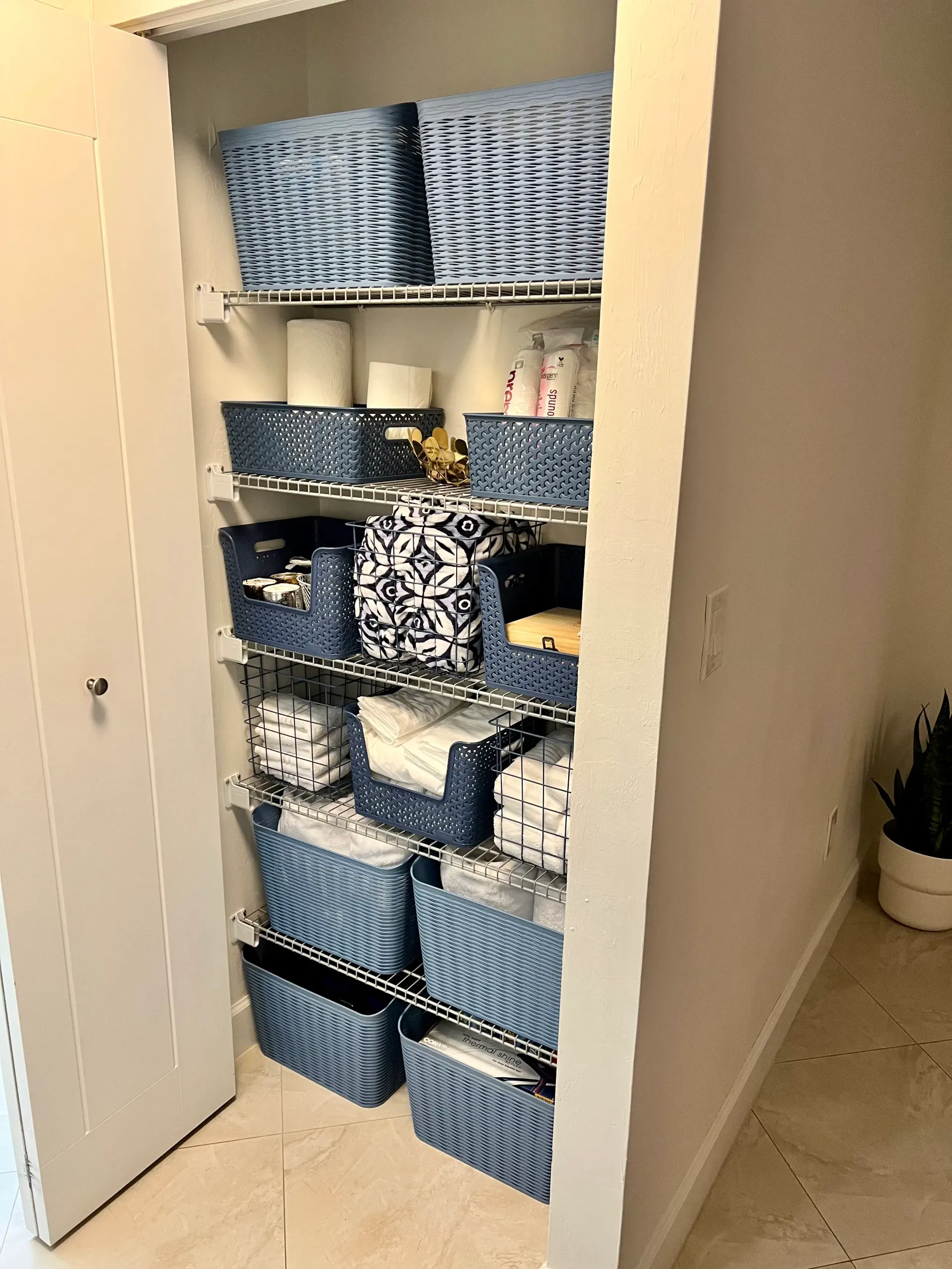 Organized linen closet with folded towels, baskets, and neatly grouped supplies