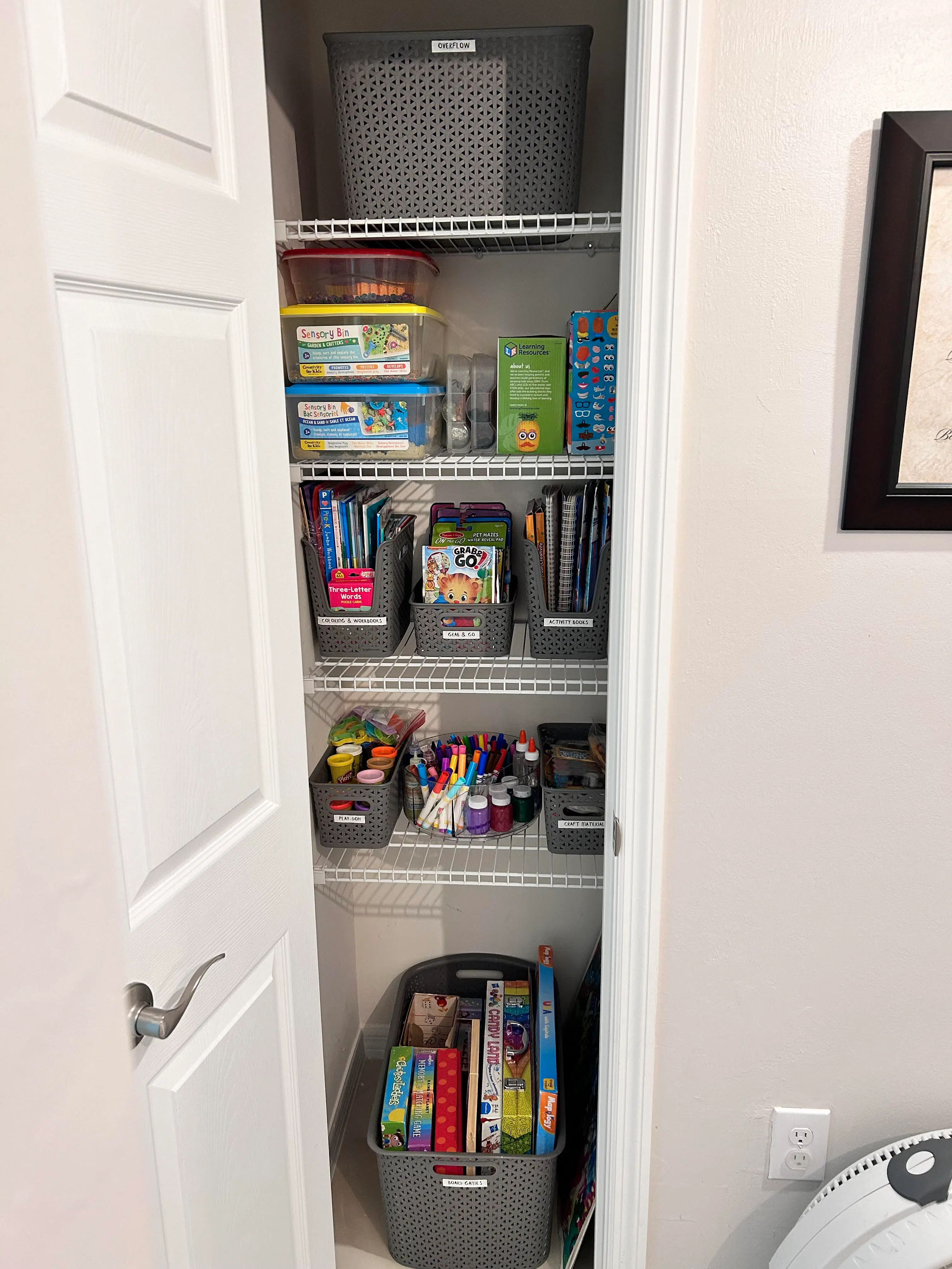 A craft and play closet with labeled bins, grouped supplies, and games arranged for easier reach and return
