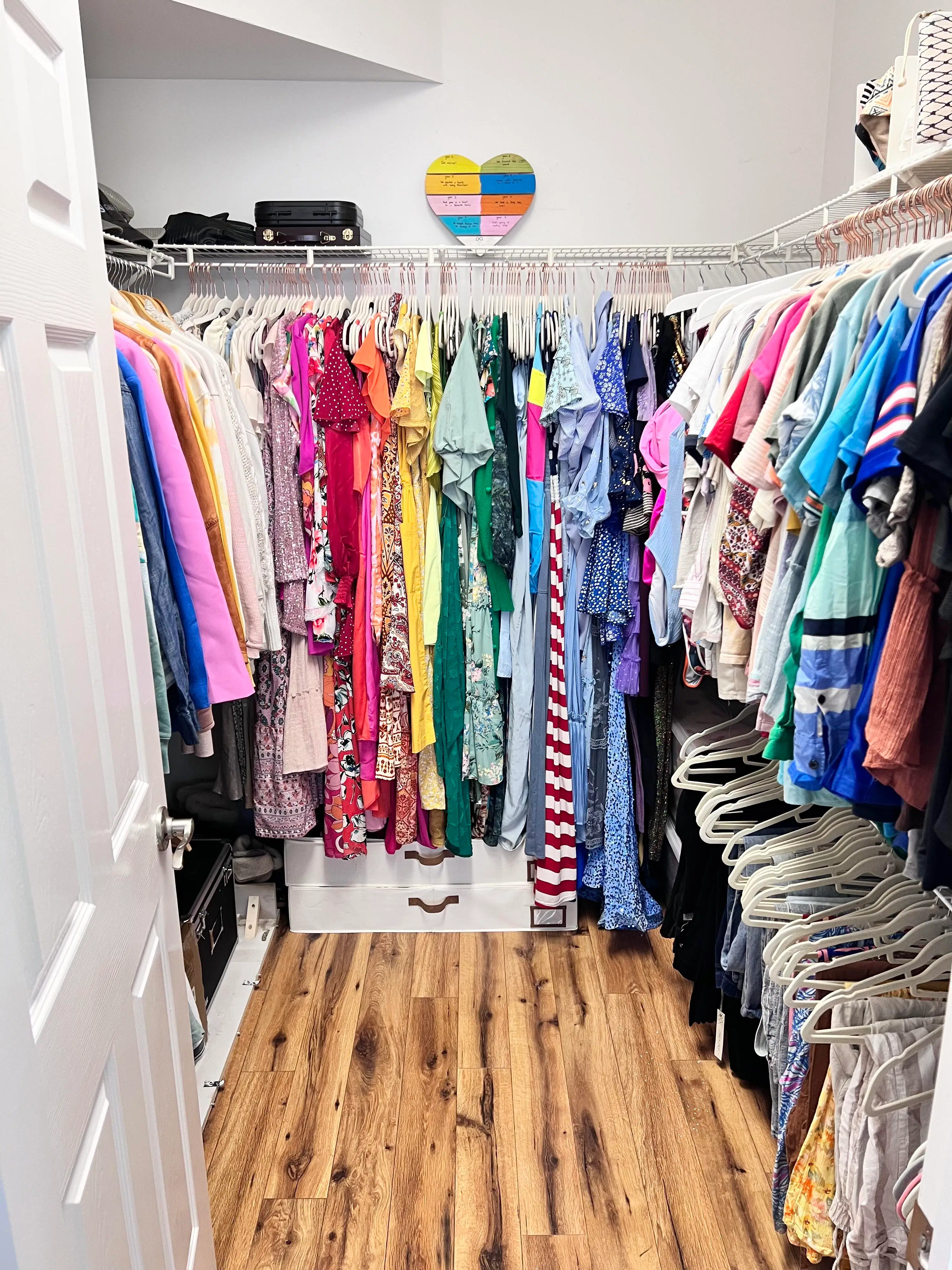 The same walk-in closet with colorful garments grouped on matching hangers, a clear floor, and open shelf space for easier dressing